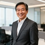 一位四十多岁的男性企业高管半身照，身穿深灰色西装，面带微笑，背景为现代化办公室环境。